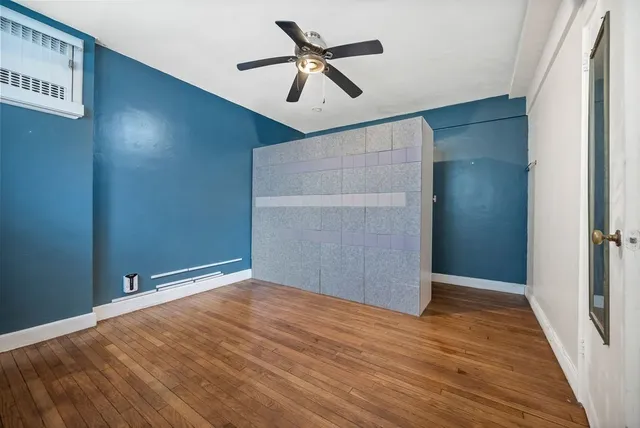an empty room with wooden floor and fan
