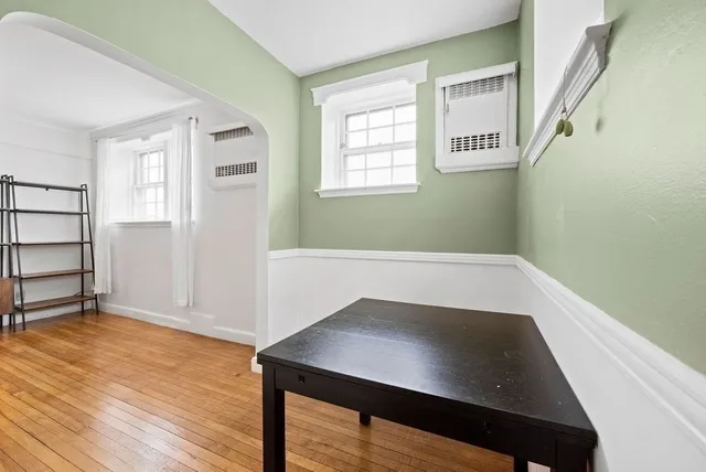 a view of an empty room with wooden floor and windows