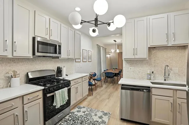 a kitchen with cabinets a sink dishwasher and a stove with wooden floor