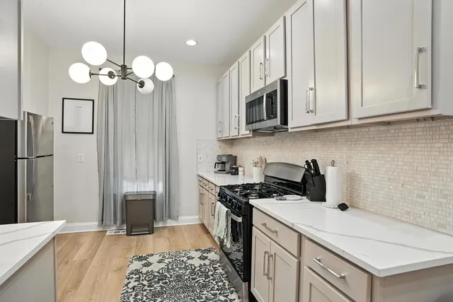 a kitchen with stainless steel appliances granite countertop a white stove a refrigerator a sink and dishwasher with wooden floor