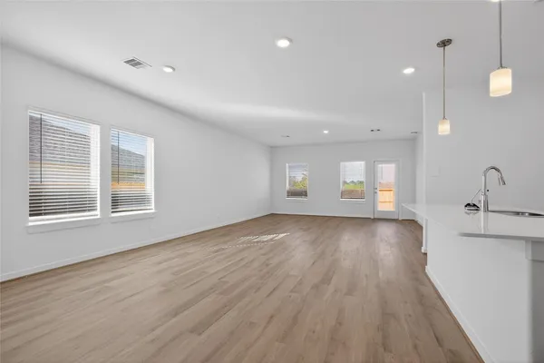 a kitchen with stainless steel appliances a sink a stove oven a refrigerator with white cabinets and wooden floor