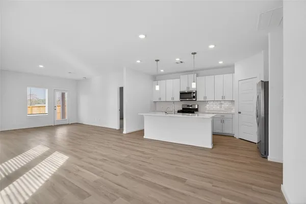a kitchen with stainless steel appliances granite countertop grey cabinets a stove a sink and a refrigerator