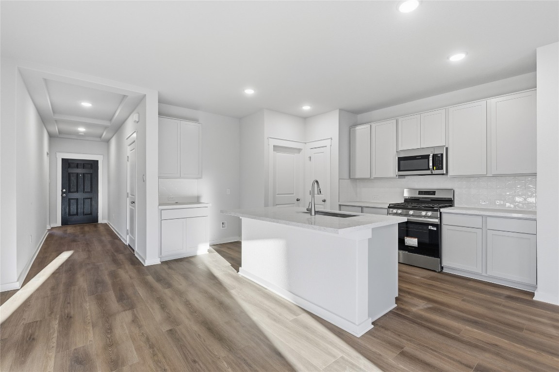 350 Mustang Bend Kyle, TX 78640 - Photo 3 of 18 Kitchen with stainless steel appliances, recessed lighting, a kitchen island with sink, white cabinetry, and decorative backsplash