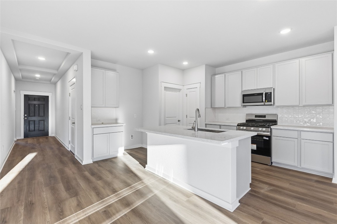 350 Mustang Bend Kyle, TX 78640 - Photo 4 of 18 Kitchen featuring appliances with stainless steel finishes, tasteful backsplash, recessed lighting, a center island with sink, and white cabinetry