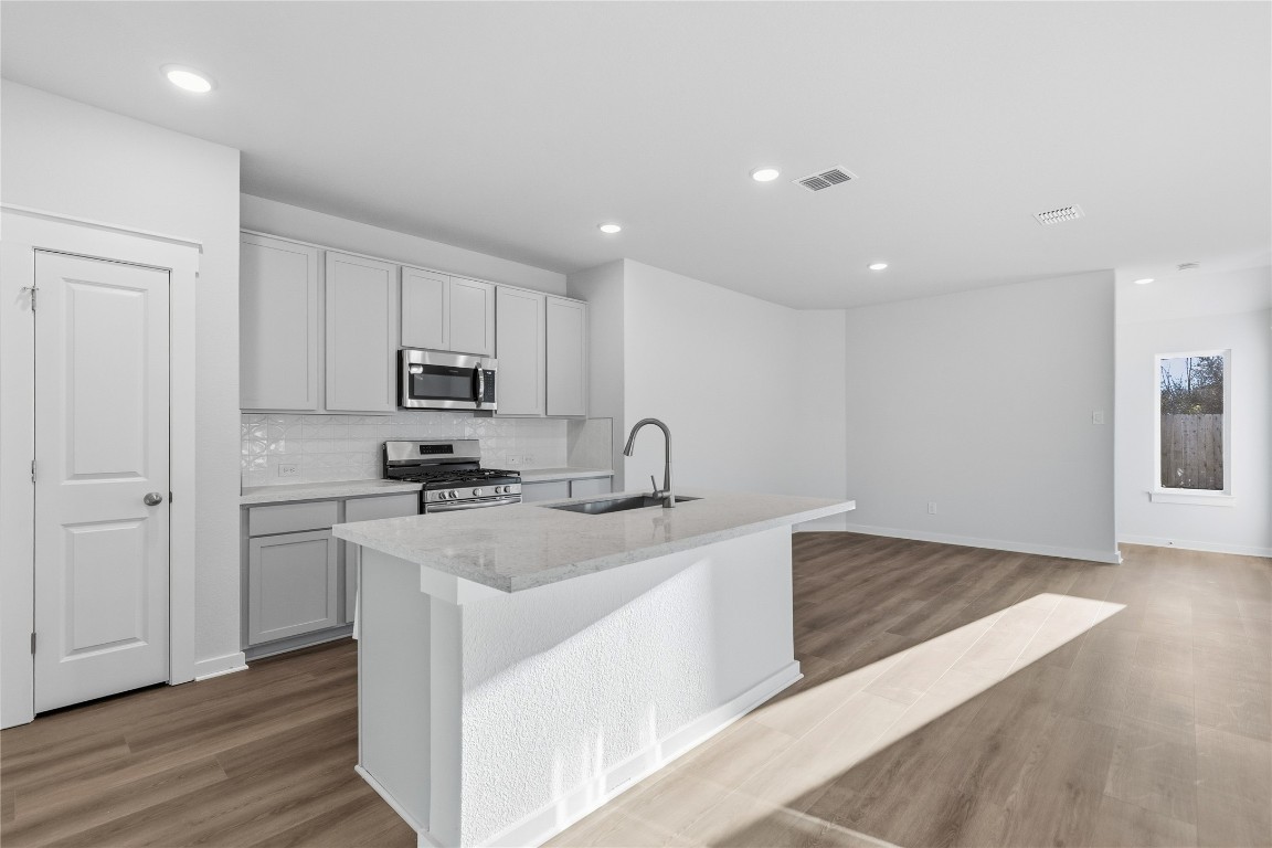 350 Mustang Bend Kyle, TX 78640 - Photo 6 of 18 Kitchen featuring appliances with stainless steel finishes, a kitchen island with sink, recessed lighting, decorative backsplash, and light stone counters