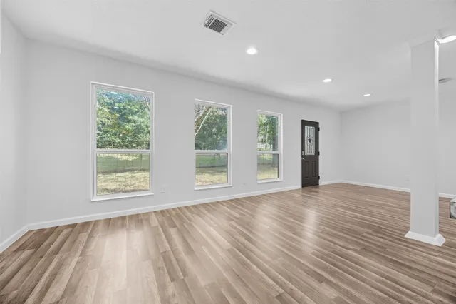 an empty room with wooden floor and windows