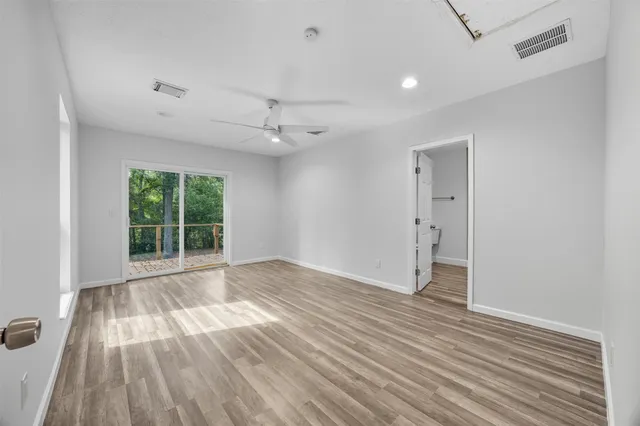 a view of an empty room with wooden floor fridge and a window