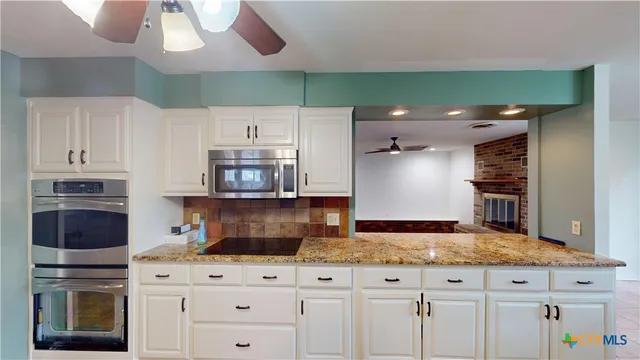 a kitchen with granite countertop a stove a sink and a microwave