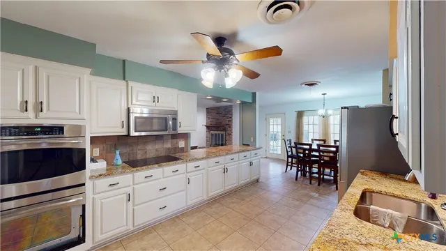 a kitchen with granite countertop a refrigerator a stove a sink a dining table and chairs with wooden floor