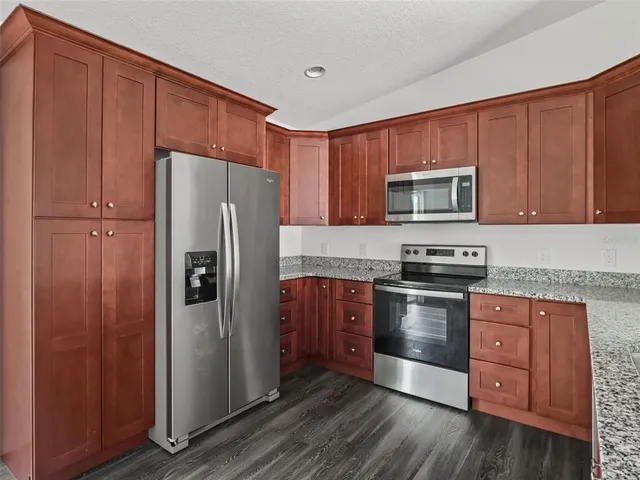 a kitchen with granite countertop a refrigerator stove and microwave