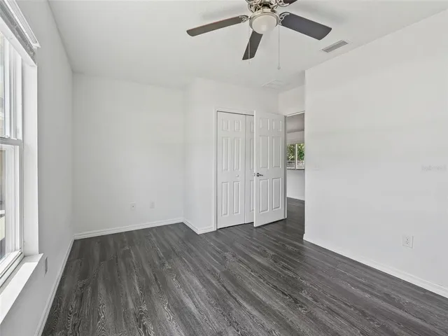 an empty room with a hardwood and ceiling fan