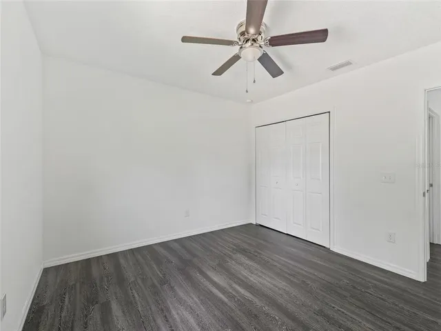 a view of a room with wooden floor and a ceiling fan