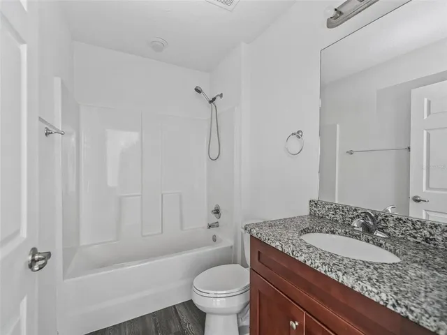 a bathroom with a granite countertop sink a toilet and shower