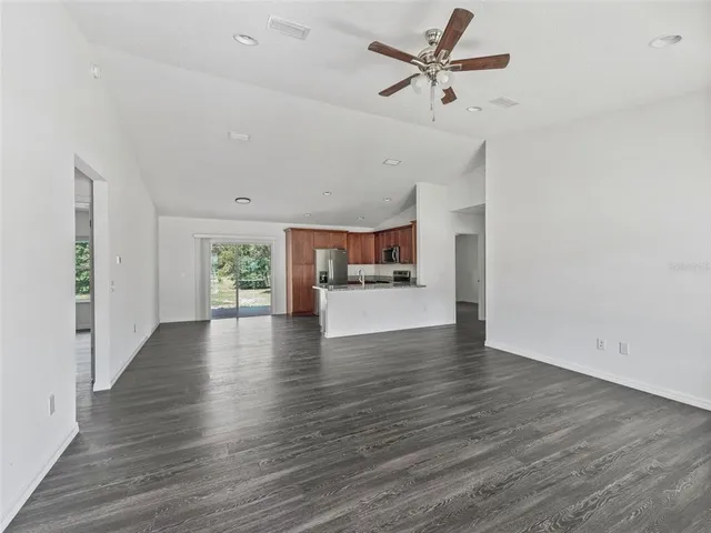an empty room with wooden floor ceiling fan and windows