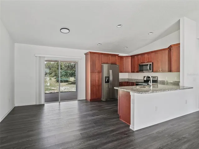 a kitchen with stainless steel appliances granite countertop a refrigerator a sink dishwasher a stove with wooden floors and a fireplace