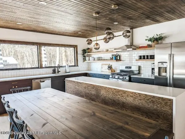 a large kitchen with stainless steel appliances kitchen island granite countertop a sink counter space and windows