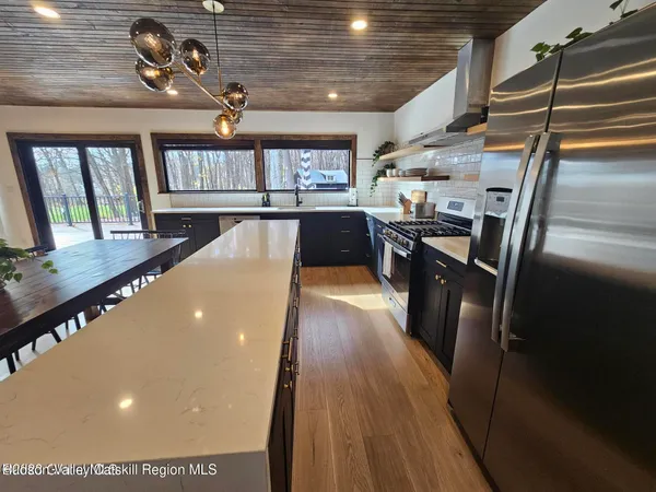 a view of a living room with stainless steel appliances wooden floor