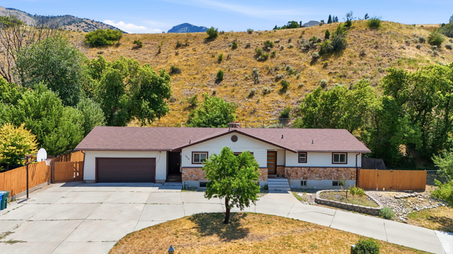 1410 Sumac Drive Logan, UT 84321 - Photo 1 of 28 Ranch-style residence featuring a detached two-car garage, a wide concrete driveway, and a fenced side yard