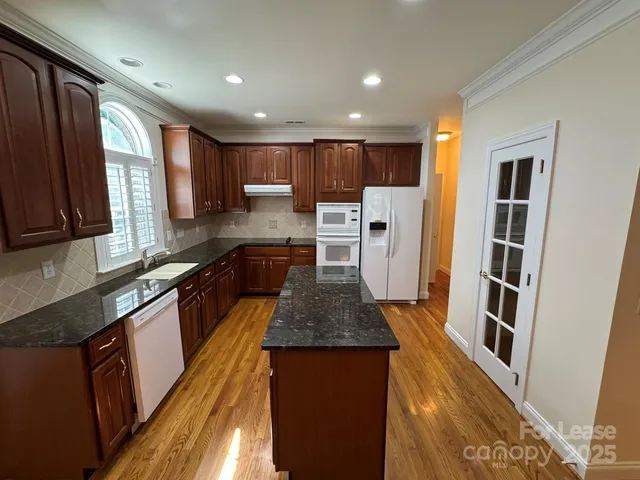 a kitchen with stainless steel appliances granite countertop a refrigerator a stove a sink and a microwave