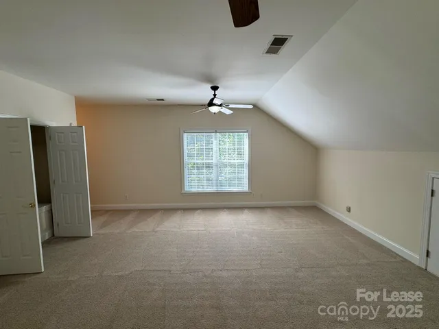 an empty room with windows and ceiling fan