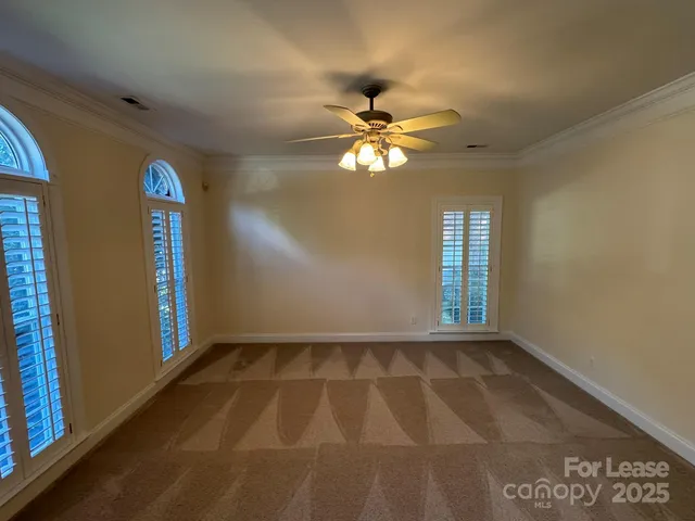 an empty room with chandelier fan and windows
