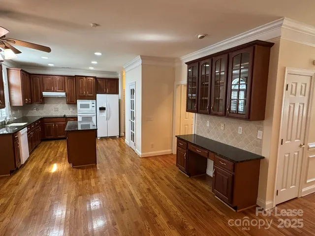 a large kitchen with stainless steel appliances granite countertop a stove and a wooden floors