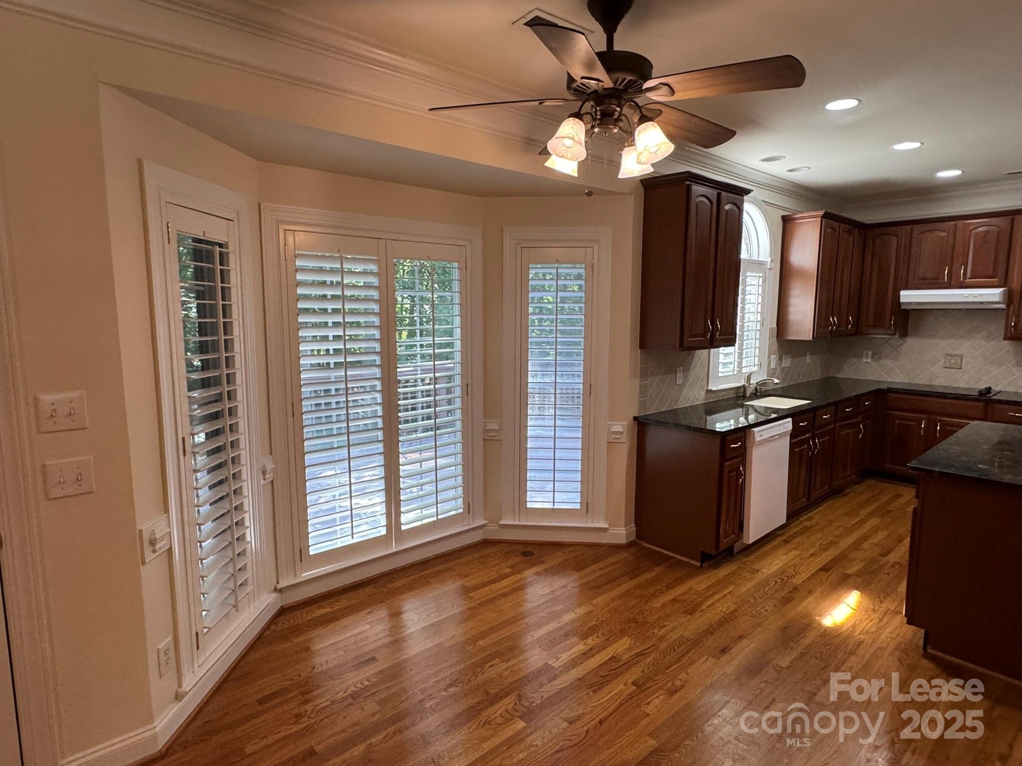 7127 Weddington Brook Drive Matthews, NC 28104 - Photo 10 of 31 a kitchen with kitchen island granite countertop a stove top oven a sink and wooden floors