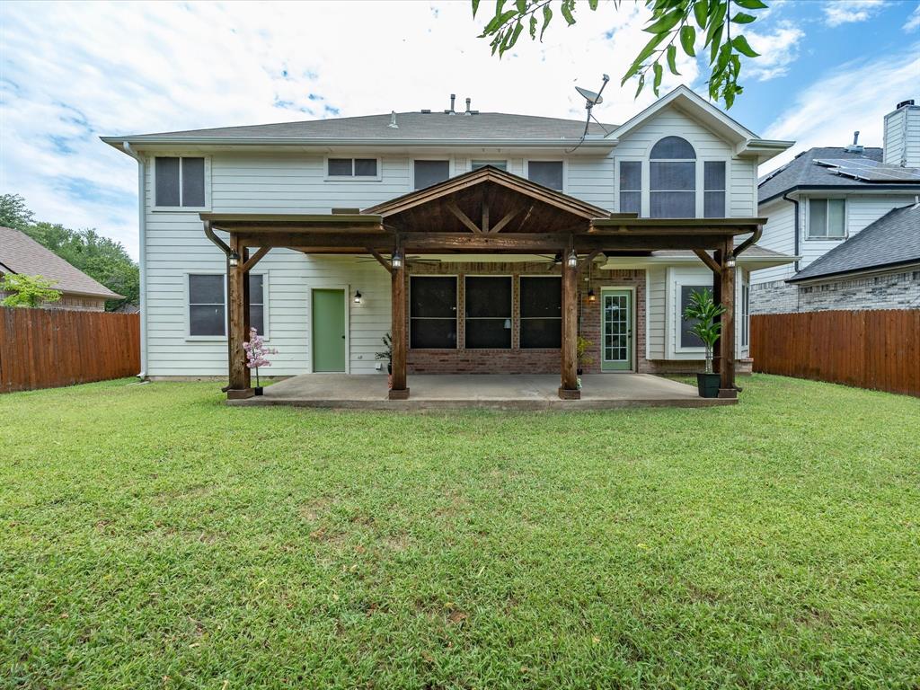4008 Falcon Ridge Drive Haltom City, TX 76137 - Photo 36 of 40 Spacious backyard featuring a covered patio with exposed wood beams, concrete slab, and brick accents