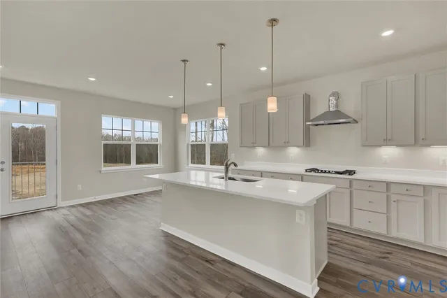 a kitchen with stainless steel appliances granite countertop a sink a stove a refrigerator and white cabinets with wooden floor