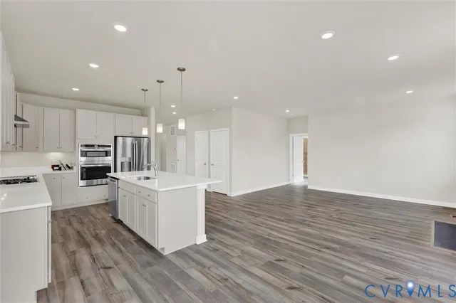 a large kitchen with a center island wooden floor stainless steel appliances and cabinets