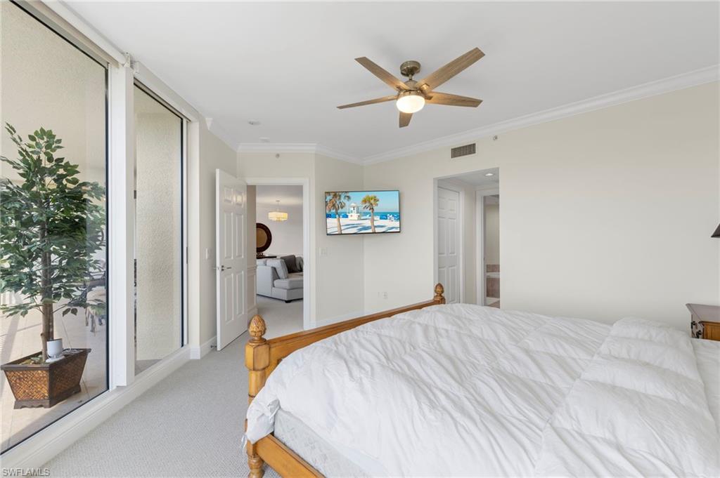 1065 Borghese Lane, Unit 403 Naples, FL 34114 - Photo 15 of 30 a bedroom with a large bed and a chandelier