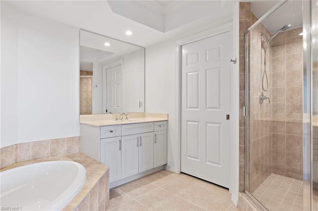 1065 Borghese Lane, Unit 403 Naples, FL 34114 - Photo 17 of 30 a bathroom with a tub sink and mirror
