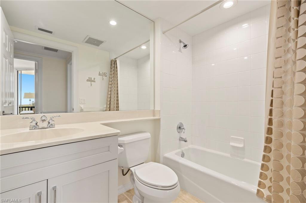 1065 Borghese Lane, Unit 403 Naples, FL 34114 - Photo 20 of 30 a bathroom with a sink a toilet a mirror a bathtub and shower