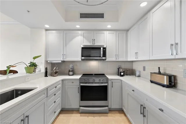a kitchen with white cabinets and black appliances