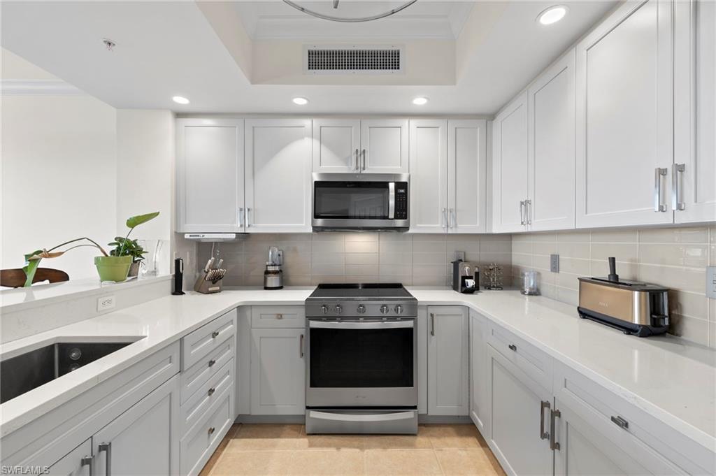 1065 Borghese Lane, Unit 403 Naples, FL 34114 - Photo 8 of 30 a kitchen with white cabinets and black appliances