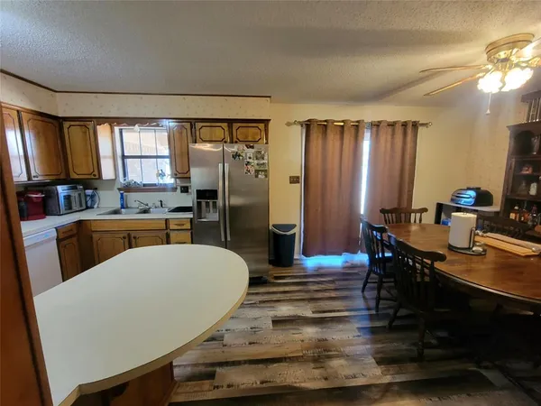 a large kitchen with sink a refrigerator and chairs