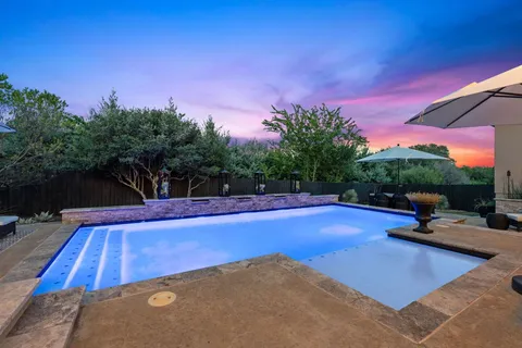 a view of a pool with a table and chairs under an umbrella