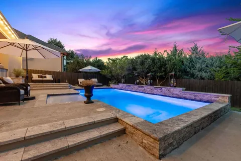 a view of a swimming pool with a table and chairs under an umbrella