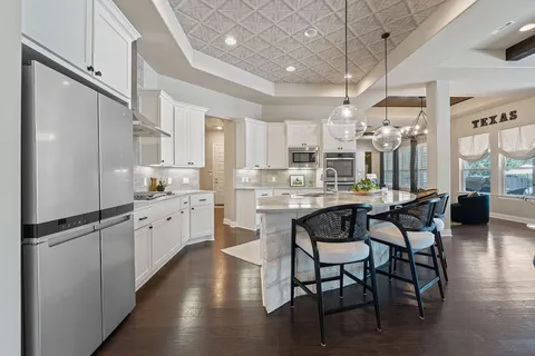 a kitchen with stainless steel appliances granite countertop a table chairs stove a refrigerator and cabinets