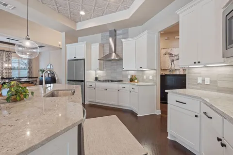 a kitchen with stainless steel appliances kitchen island granite countertop a refrigerator a stove a sink dishwasher and white cabinets with wooden floor