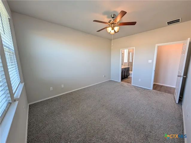 an empty room with windows and fan