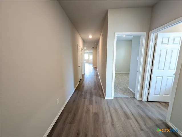 a view of a hallway with wooden floor and staircase