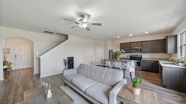 a living room with furniture kitchen view and a wooden floor