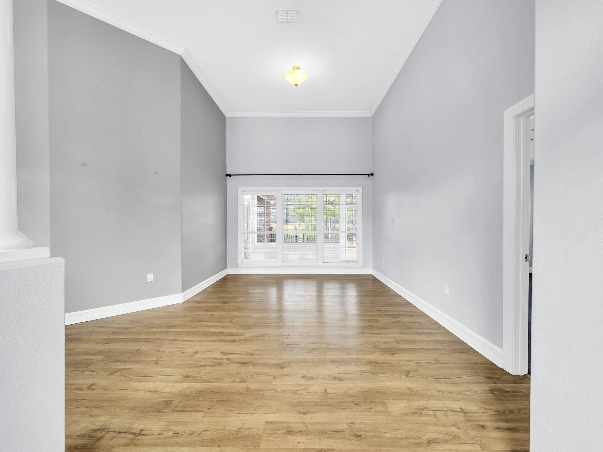 180 Gulf Pines Court Freeport, FL 32439 - Photo 11 of 70 a view of an empty room with wooden floor and windows