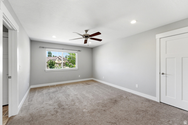 1614 Aspen Loop Provo, UT 84606 - Photo 34 of 47 Spacious room featuring neutral carpeting, light gray walls, a window with white trim, recessed lighting, and a ceiling fan