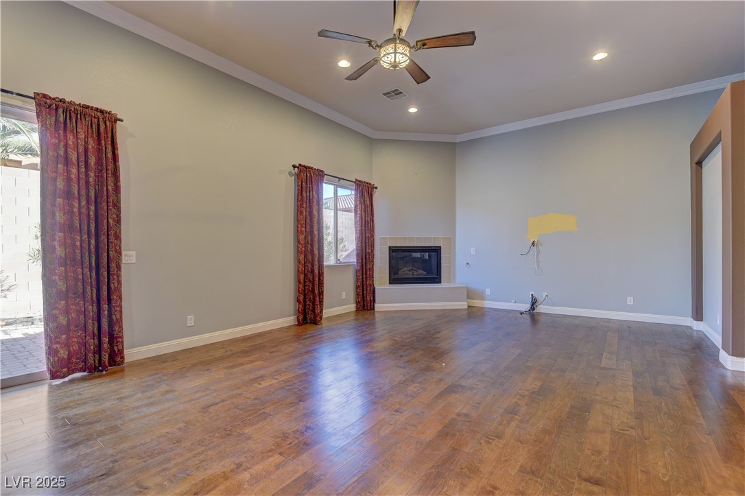 972 Rue Grand Paradis Lane Henderson, NV 89011 - Photo 9 of 32 Unfurnished living room with crown molding, a fireplace, dark wood-style flooring, a ceiling fan, and recessed lighting