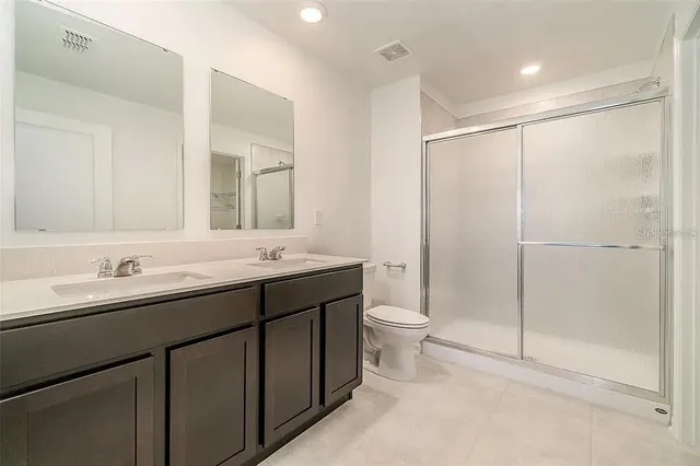 a bathroom with a double vanity sink mirror and toilet
