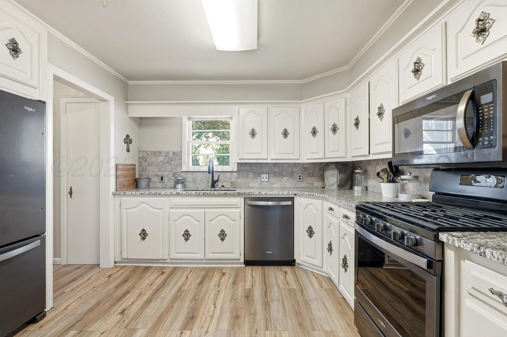 700 West Cleveland Street Dimmitt, TX 79027 - Photo 12 of 40 a kitchen with granite countertop white cabinets and white appliances