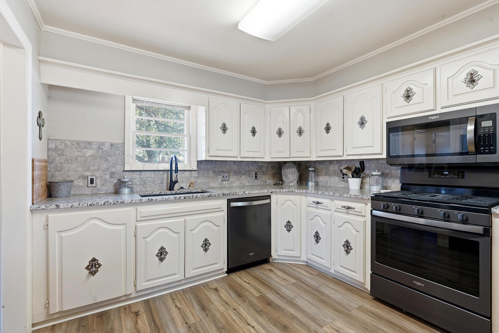 700 West Cleveland Street Dimmitt, TX 79027 - Photo 14 of 40 a kitchen with stainless steel appliances granite countertop a stove a sink and white cabinets