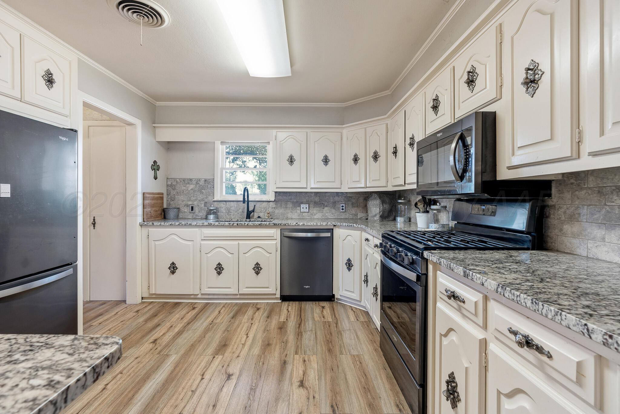 700 West Cleveland Street Dimmitt, TX 79027 - Photo 15 of 40 a kitchen with stainless steel appliances granite countertop a stove a sink dishwasher and a refrigerator with white cabinets